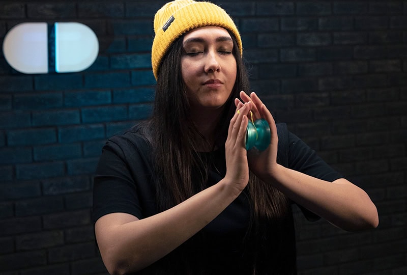Player in a yellow beanie holding a teal yoyo for the Stop and Go trick