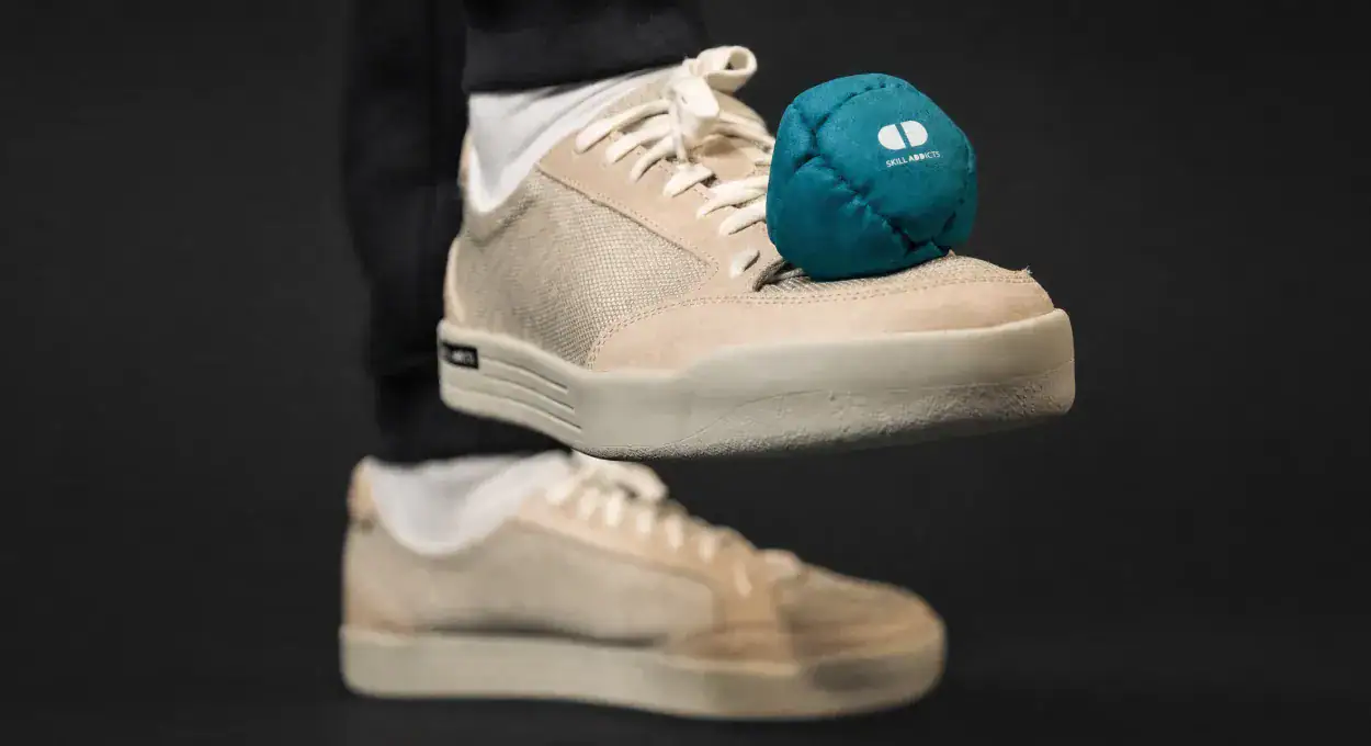 Close-up of a beige Quantum shoe kicking a teal footbag