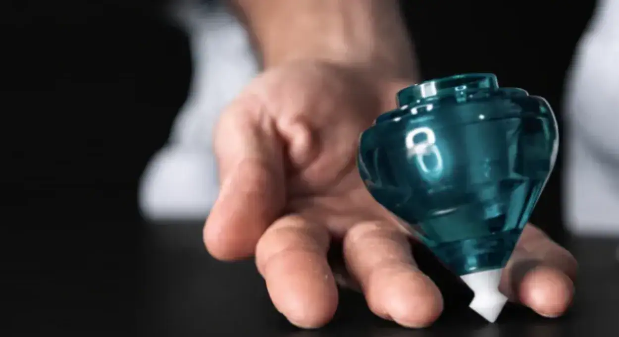 Teal Classic Fixed Spin Top spinning on an open hand