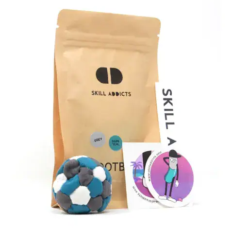 Pro Footbag in teal, grey and white with its kraft paper bag and stickers