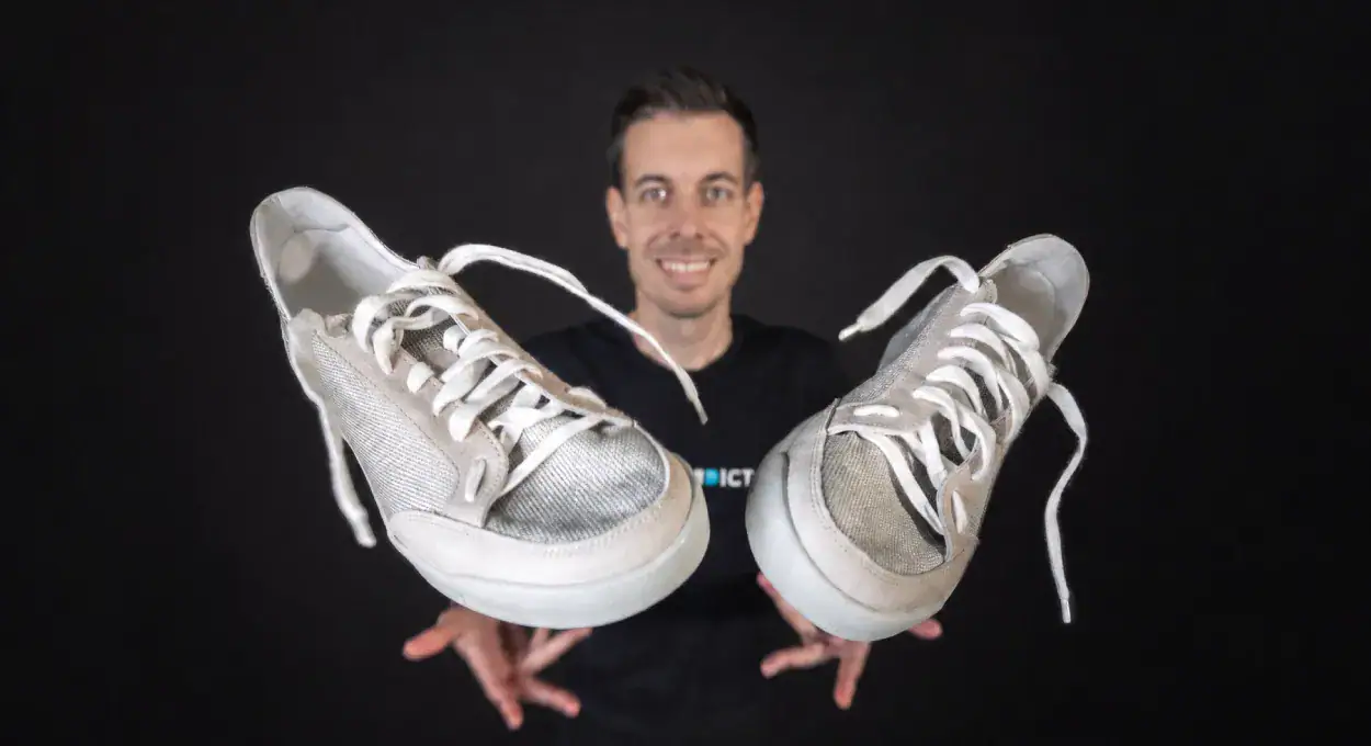 Player holding out a pair of beige Quantum Hacky Sack Shoes