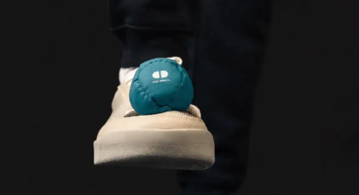 Teal Starter Footbag balanced on the toe of a beige shoe